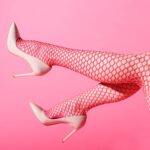 Rosa High Heels und rote Netzstrumpfhose auf pinkem Hintergrund, stilvolles Accessoire für International Escort.